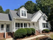 Charming home with a covered porch, grey shutters, gray roof, brick trim, and mature landscaping at 3212 Potthast Ct, Raleigh, NC 27529