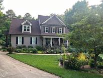 Charming two-story home with a landscaped yard, beautiful flower beds, and a welcoming covered porch at 3581 Boulder Ct, Wake Forest, NC 27587