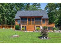 Charming log cabin with a screened porch, wooden deck, and beautifully landscaped front yard at 52 Buoy Dr, Henderson, NC 27537