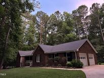 Charming brick home with a well-maintained lawn and mature trees surrounding the property at 7194 Johns Point Ct, Liberty, NC 27298