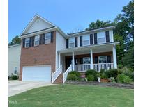 Charming two-story home with brick accents, white siding, a covered porch, and a well-manicured front yard at 1126 Woodlands Creek Way, Apex, NC 27502