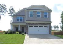 Charming two-story home with a well-manicured lawn, stone accents, and an attached two-car garage at 124 Richmond Run, Stem, NC 27581