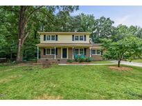 Charming two-story home with a brick and yellow exterior, a covered front porch, and a green lawn at 1704 Little John Ct, Burlington, NC 27217