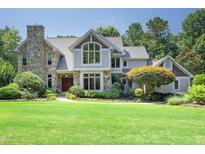 Beautiful two-story home featuring a stone chimney, large windows, a manicured lawn, and mature landscaping at 267 Bald Eagle Dr, Pittsboro, NC 27312