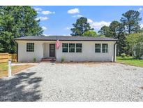 Charming renovated home with gravel drive, white painted brick, black roof and trim and lovely yard at 311 Troy St, Creedmoor, NC 27522