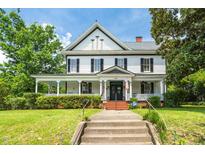 Charming two-story home with black shutters and a welcoming front porch, framed by lush greenery at 401 N Main St, Louisburg, NC 27549