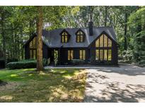 Charming exterior view of the home featuring large windows, a dark facade and mature trees at 5217 West Oaks Dr, Fuquay Varina, NC 27526