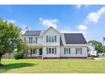 Charming two-story home with solar panels, inviting front porch, and well-manicured lawn at 73 Lynnville Ct, Lillington, NC 27546
