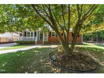Charming single-story brick home featuring a welcoming front porch and mature trees at 908 Clarion Dr, Durham, NC 27705