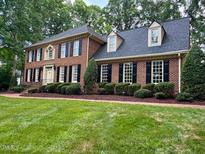 Traditional two-story brick home with lush lawn and manicured landscaping at 105 Abbotsford Ct, Durham, NC 27712