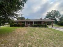 Charming single-story brick home with a well-maintained lawn and mature trees at 1116 Friendly Rd, Dunn, NC 28334