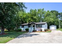 Charming home featuring a manicured lawn, lush landscaping, and a driveway leading to a detached storage shed at 1344 Highland Dr, Wake Forest, NC 27587
