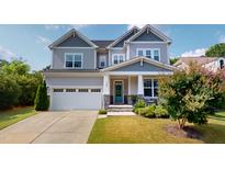 Charming two-story home with a well-manicured lawn, a turquoise front door, and a two-car garage at 1880 Woodall Crest Dr, Apex, NC 27502