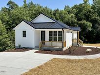 Charming new construction home with white siding, a black metal roof, and a well-manicured lawn at 205 Gentry St, Roxboro, NC 27573