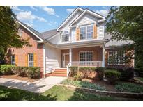 Charming two-story home featuring a brick and siding exterior, a front porch, and well-maintained landscaping at 2613 Sweet Gum Dr, Hillsborough, NC 27278