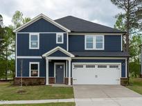 Charming two-story home with navy siding, white trim, a two-car garage, and a well-maintained lawn at 3813 Rosebush Dr, Zebulon, NC 27597
