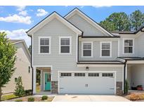 Charming townhome featuring a two-car garage, teal front door, and gray siding at 479 Clark Creek Ln, Cary, NC 27519