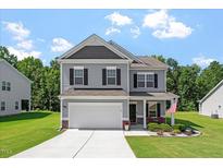 Charming two-story home featuring gray siding, black shutters, and a well-manicured lawn on a sunny day at 534 Lionheart Ln, Sanford, NC 27330