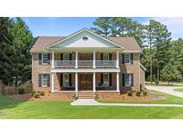 Two story brick home with manicured lawn, a symmetrical facade, and a welcoming front porch with seating at 55 Fleming Forest Dr, Youngsville, NC 27596