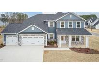 Beautiful two-story blue home featuring a three car garage and landscaped front yard at 55 Shoreline Dr, Lillington, NC 27546