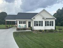 Charming one-story home featuring a landscaped front yard, covered driveway and cozy porch with seating at 8 Open View Ln, Timberlake, NC 27583