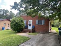 Charming brick home features a small porch, manicured lawn, and a paved driveway leading to the detached garage at 1021 Delray St, Durham, NC 27713
