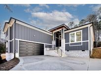 Beautiful gray home showcasing a two-car garage, stylish entryway, and white brick base and accents at 110 Mohave Dr, Louisburg, NC 27549