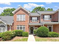 Charming brick townhome with a manicured lawn and a welcoming front door wreath at 1505 Poets Glade Dr, Apex, NC 27523