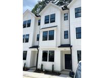 Modern townhome exteriors featuring white siding, black framed windows, and contemporary design elements at 1531 Crescent Townes Way, Raleigh, NC 27604