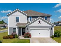Charming two-story home featuring gray siding, a two-car garage, and well-maintained landscaping with a red star above the garage at 217 Windy Knoll Dr, Graham, NC 27253