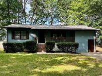 Charming single story home with green paint, brown trim, and covered porch at 424 Shawnee Dr, Louisburg, NC 27549