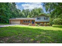 Two-story home featuring a brick and siding exterior, attached garage and green lawn at 6308 Rolling Acres Drive, Gibsonville, NC 27249