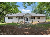 Charming brick ranch home with a new roof and black shutters surrounded by mature trees at 7722 Nc 27, Lillington, NC 27546