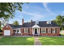 Charming brick home with a well-manicured lawn, black shutters, and a welcoming entrance at 201 N Us 301, Micro, NC 27555