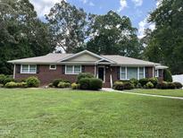 Charming brick home features mature landscaping, a well-manicured lawn, and inviting curb appeal at 211 Hillcrest Dr, Oxford, NC 27565