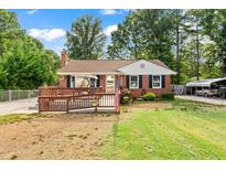 Charming brick ranch home featuring a spacious wooden deck and well-maintained front yard at 306 Mitchell Ave, Franklinton, NC 27525