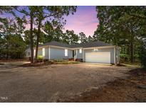 Charming single-story home featuring a two-car garage and a gravel driveway at dusk at 74 Dove Trl Trl, Sanford, NC 27332