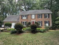 Charming brick two-story home with black shutters, a red front door, and mature landscaping at 7905 Breda Ct, Raleigh, NC 27606