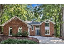 Traditional brick home surrounded by mature trees with a well manicured front yard and a paved driveway at 103 Javelin Ct, Cary, NC 27513