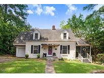 Charming white home with dormer windows, black shutters, front porch and a well-manicured lawn at 115 Person St, Louisburg, NC 27549