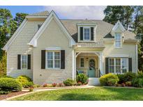 Charming home featuring a brick facade, black shutters, and a beautifully landscaped front yard with a light blue front door at 321 Wescott Ridge Dr, Holly Springs, NC 27540