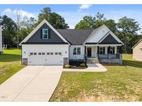Charming, newly built, single-story home with white siding, black roof and shutters, and a two-car garage at 359 Carolina Landing Dr, Zebulon, NC 27597