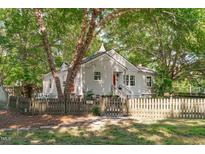Charming home featuring a picket fence and a bright red front door, surrounded by lush trees at 501 E Spring St, Fuquay Varina, NC 27526