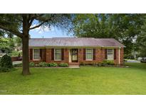 Charming brick home with a metal roof, complemented by a lush green lawn and mature trees at 516 Ivey Rd, Graham, NC 27253
