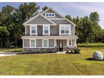 Beautiful two-story home featuring gray siding, stone accents, green lawn and manicured landscaping at 5215 Goshawk Ln, Graham, NC 27253