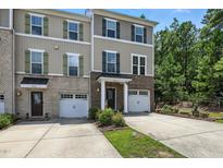 Traditional townhouse with a brick and siding facade, attached garage, and well-maintained landscaping at 651 Berry Chase Way, Cary, NC 27519