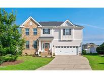 Charming two-story home featuring a blend of brick and siding, manicured lawn, and an attached two-car garage at 1002 Meridian View Ct, Knightdale, NC 27545