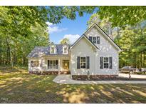 Charming two-story home featuring a welcoming front porch, lush landscaping, and a private wooded lot at 105 Timberlands Dr, Louisburg, NC 27549