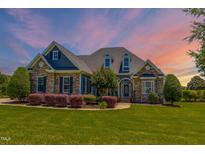 Inviting stone and vinyl home with manicured lawn and colorful landscaping at 2009 Rockwall Farms Ln, Fuquay Varina, NC 27526