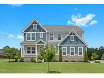 Charming two-story home featuring stone accents, a welcoming porch, and a beautifully landscaped front yard at 300 Ledge Manor Dr, Holly Springs, NC 27540